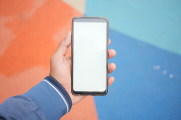 top view of hand holding a smart phone with empty screen on color background 