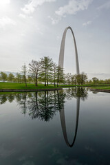 Gateway Arch reflected in reflecting pool in Gateway Arch National Park in Saint Louis, Missouri under dramatic spring cloudscape. - obrazy, fototapety, plakaty
