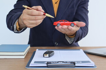 Businessman with car insurance documents. He is a male. Car insurance protects his vehicle....