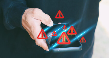 Notification smartphone concept. A young man using a phone with a warning symbol indicating the risk of data theft, Hacking passwords, and personal data.	