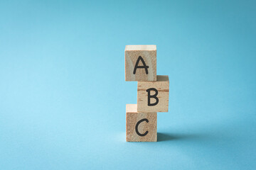 Three toy wooden blocks with letters ABC on them. On blue background, copy space.

