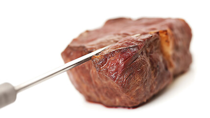 A juicy, cooked steak pierced with a fork against a white background.