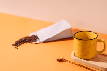Yellow mug with spoon and coffee beans.