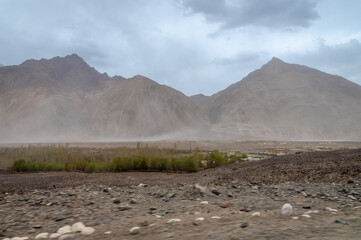 Sand Storm in the cold desert of Nubra Valley in Ladakh, India. Background of Himalayas and dramatic clouds. View from a rocky road in the Himalayas. 