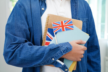 Learning English, Asian teenage student holding book with flag for language program education.
