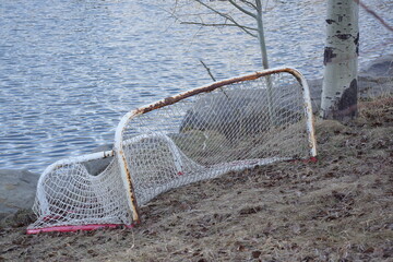 Rusty broken soccer net in front of pond waves