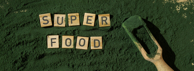 Wooden blocks with text SUPERFOOD chlorella on background of algae superfood powder. Healthy...