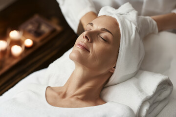 Beautiful mature woman face, massage table in spa salon. Cosmetic skin care procedures.