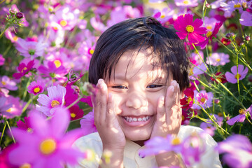 Happy little Asian boy kid smiling in the pink flowers garden.