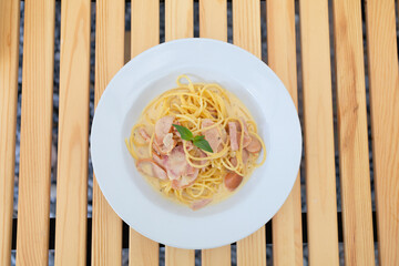 Italian Spaghetti Carbonara in a white dish on wooden table.