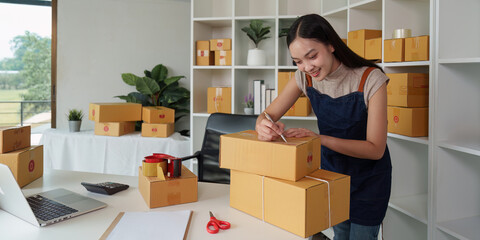 Fototapeta na wymiar A woman entrepreneur working at home office and prepare a parcel before delivery