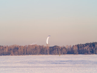 Kite surfer ride on snowboard. Snowkiting in the snow on frozen lake.