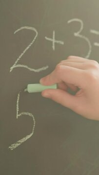 Schoolgirl writes mathematical examples on blackboard