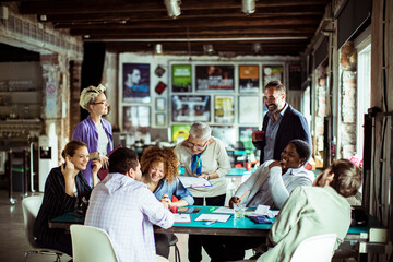 Multigenerational and diverse group of people working on a project together in a startup company office