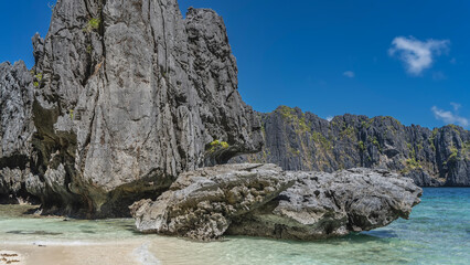 Beautiful karst rocks with bizarre outlines rise above the aquamarine lagoon. There is green...