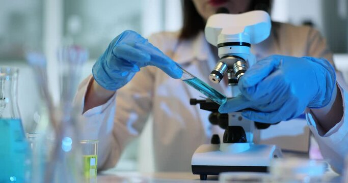 Scientist holding and looking at a test tube with blue liquid in the laboratory