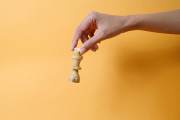 Woman hand holding chess piece isolated on yellow background