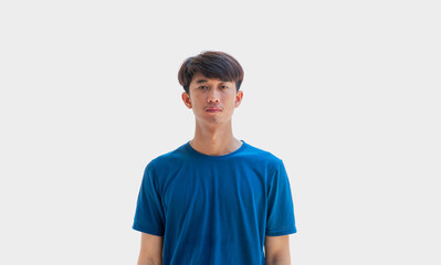 A young Asian man in his 20s wearing blue t-shirt is depressed and worried in distress standing on a gray background. Crying in anger and fear. Sad expression concept