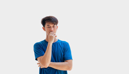 A young Asian man in his 20s wearing a blue t-shirt standing thinking isolated on a gray background. A man stressed out by problems going through life. tension concept