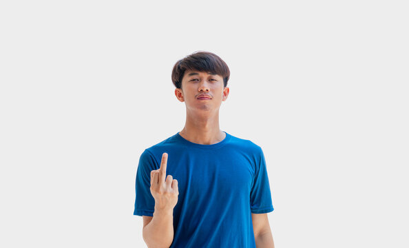 A young Asian man in his 20s wearing a blue t-shirt makes a gesture of showing your middle finger and scolding Fuck You isolated on a gray background