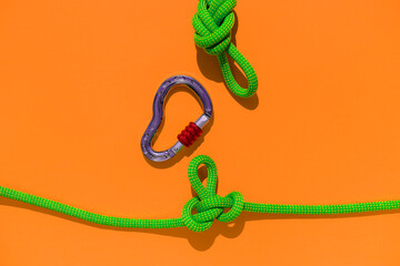 rope with a secure knot and a carabiner lies on a colored background. Equipment for rock climbing and mountaineering. reliable connection. concept of reliability and strength. - 793567401