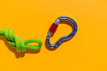 carabiner with a rope lies on a colored background. Equipment for climbing and mountaineering. reliable connection. Safety rope.  the concept of reliability and strength. - 793567813