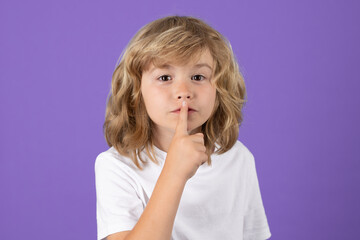 Cute kid with show no talk gesture. Boy with shows shh sign. Be quiet. Hush dont tell. Child put finger to lips mouth, ask stop share rumor, isolated over studio isolated background.