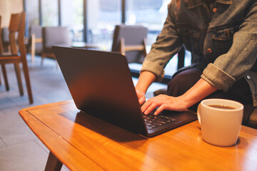 Closeup image of a woman working and typing on laptop computer in cafe
