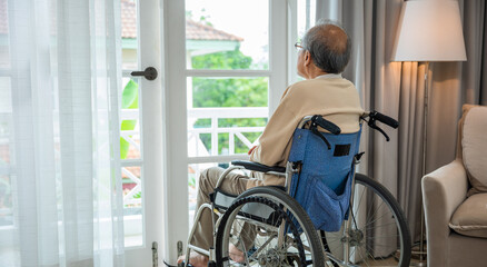 Lonely older thoughtful sad old man look outside windows in bedroom at retirement home, Asian...