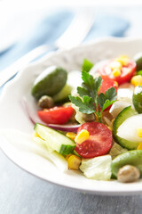 Simple Salad with Green Olives, Cucumber and Cherry Tomatoes. Bright wooden background.	