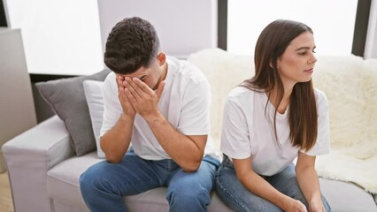 A man and woman show distress and comfort in a well-lit modern living room, depicting relationship issues.