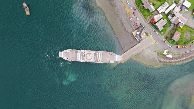 Aerial Birds Eye View Of Ferry Boat Docked At Ramp In Hornopiren Town Located In Commune Of Hualaihué in Palena Province, Southern Chile. Pedestal Down