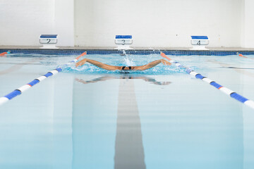 Biracial young female swimmer wearing goggles reaching end of the swimming pool lane, copy space