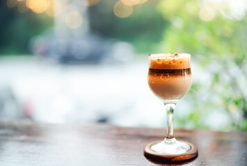 Cafe latte macchiato layered,Glass of coffee cup on wooden table with blurry sunlight background,...