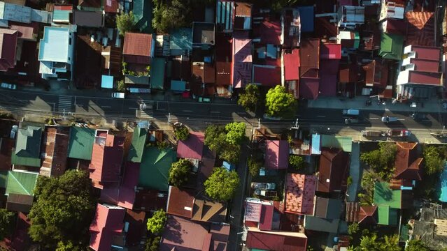 Birds eye aerial above cars driving in middle of houses, in Luzon, Philippines