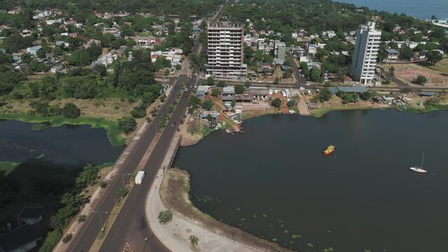 Immersive drone footage captures the picturesque aerial of the Panara River, featuring a bustling bridge, vehicles on the road, construction buildings, lush green trees, and charming houses.