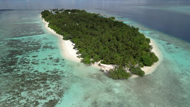 Aerial drone video flying backwards to reveal the local island of Thinadhoo in the Maldives.