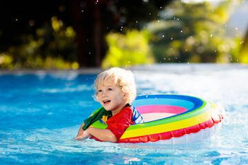 Child in swimming pool on toy ring. Kids swim. - 793606080