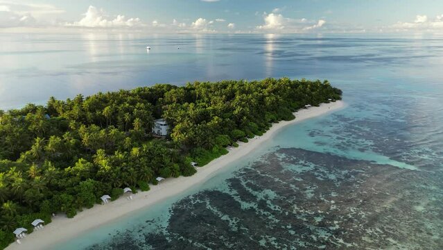 Aerial drone footage slowly panning and descending along the Bikini Beach of the local island of Thinadhoo in the Maldives at sunrise.