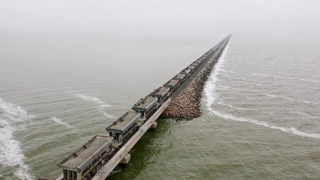 Aerial of long freight train carrying rocks by Lake Picasa, Argentina