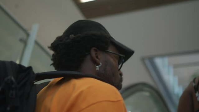 Close-up of African American man with fashionable silver earring riding escalator with contemplative facial expression