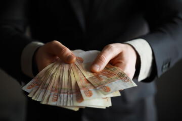 a man in an expensive suit holds a lot of money in his hand, Russian rubles, bills of five thousand...