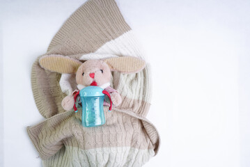 A stuffed rabbit toy holds a baby bottle of blue color