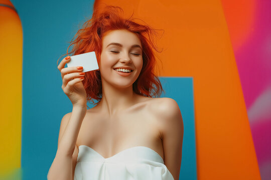 Beautiful female model holding blank credit card on a colorful background