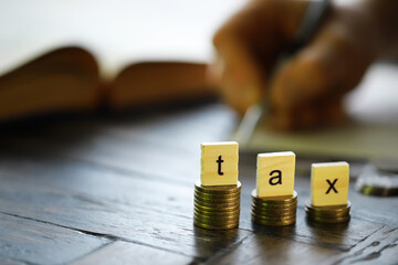 Tax Concept with wooden block on stacked coins