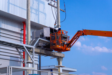 Electrical technician working inspection works on the power transformer before start operation in site constuction ,Electrical engineer working on boom lift for inspection power transformer  © Kittisak