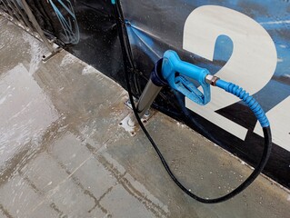 The gun for washing a car at a blue car wash is placed in a special metal niche. The topic of car washing and maintenance.