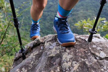 Suceesful woman hiker legs climbing up on mountain peak cliff edge