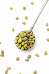 Dry, green mung beans in iron spoon on white background