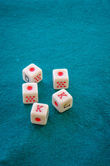 Dice for playing poker, with three figures of the ace and two of the king, on a green mat.